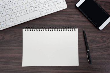 Bilgisayarlı, klavyeli, kalemli, not defterli ve akıllı telefonlu ofis masasının tam üstünde. Düz yatıyordu. Boşluğu kopyala.