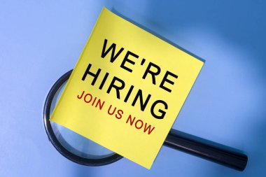 Mavi arka planda büyüteçle yapıştırılmış yapışkan not metni için bize katılın. İş Konsepti.