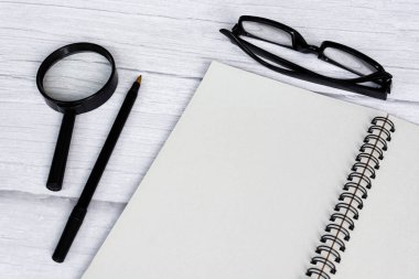 Notepad düz, büyüteç ve kalemle beyaz ahşap masa üzerinde yatıyordu. Tam üstte. Boşluğu kopyala.