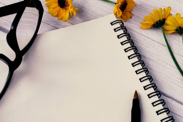 Note book flat lay with sunflowers on wooden desk. Directly above. Copy space.
