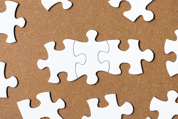White jigsaw puzzle on wooden background. Directly above. Flat lay. Copy space.