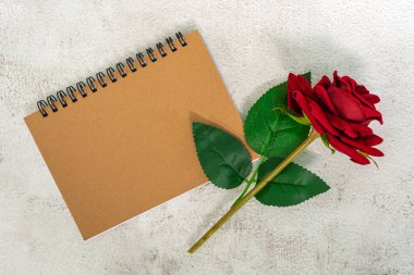 Üzerinde kırmızı güller olan kahverengi not defteri. Tam üstte. Düz yatıyordu. Boşluğu kopyala.