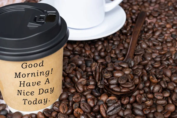 Motivational quote on disposable coffee cup on coffee beans background - Good morning, have a nice day today.