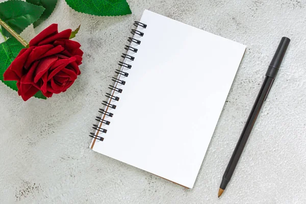 Note book with pen and roses on marble table. Directly above. Flat lay. Copy space.