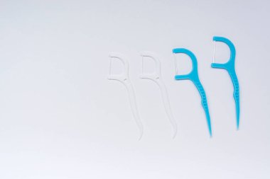White and blue floss toothpicks on white background. Directly above. Flat lay. Copy space.