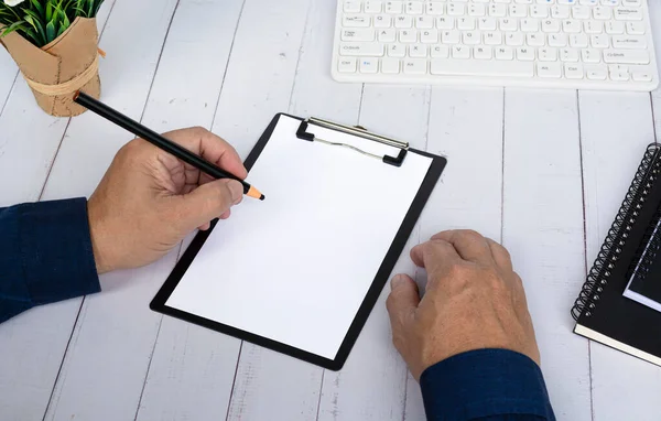 Hand with pencil writing something on the black clipboard. Copy space. Business and education concept.