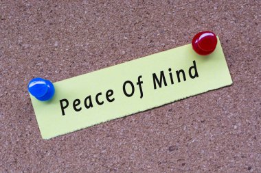 Peace of mind words on stick note and pinned to a cork notice board. Motivational quote.