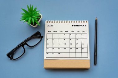 February 2023 desk calendar on blue background. Directly above. Flat lay. Copy space.