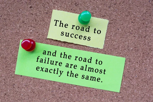 Motivational quote on stick note and pinned to a cork notice board. The road to success and the road to failure are almost exactly the same.