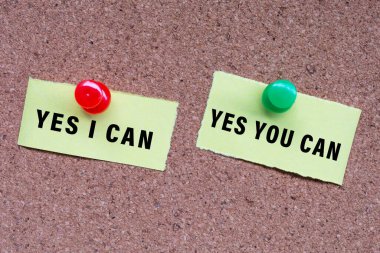 Yes I Can and Yes You Can words on stick note and pinned to a cork notice board. Teamwork and business concept.