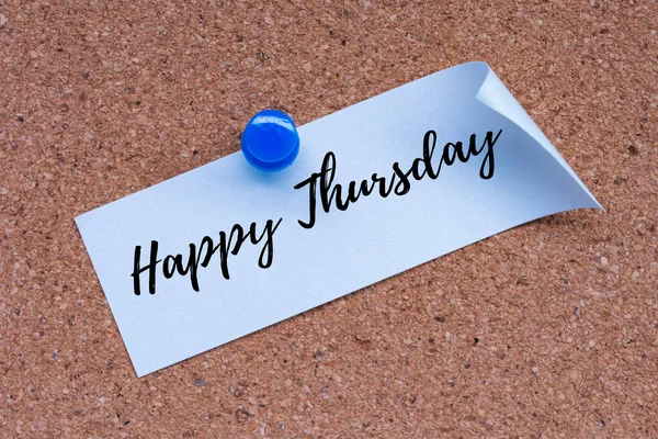 Happy Thursday word on white stick note and pinned to a cork notice board.