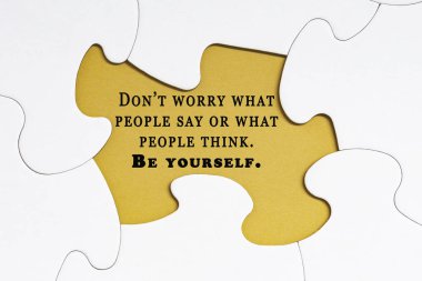 Motivational quote on white jigsaw puzzle with some missing pieces on yellow background - Don't worry what people say or what people think. Be yourself.