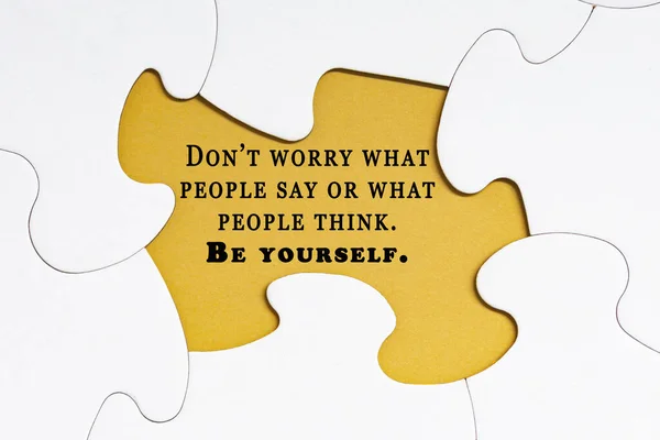 Motivational quote on white jigsaw puzzle with some missing pieces on yellow background - Don\'t worry what people say or what people think. Be yourself.