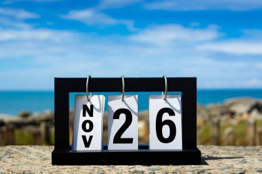 Nov 26 calendar date text on wooden frame with blurred background of ocean. Calendar date concept.