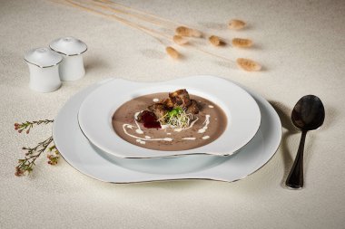 Kızarmış et ve bezelye filizli sebze çorbası. Tabağı masaya servis etmek ve beyaz bir masa örtüsüne bir kaşık ve peçeteyle süslemek.