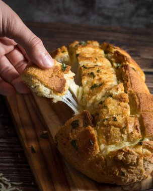 Bir dilim sarımsaklı ekmek, peynir ve maydanozlu.