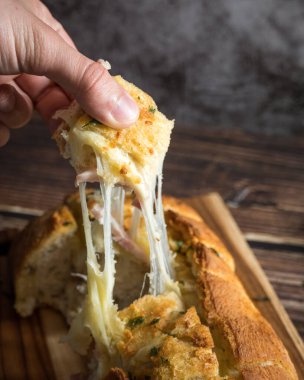 Bir dilim sarımsaklı ekmek, peynir ve maydanozlu.