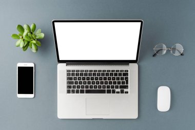 Bilgisayarlı, boş ekranlı ve gri masadaki aksesuarlı iş geçmişi. Ofis masaüstü. Üst görünüm