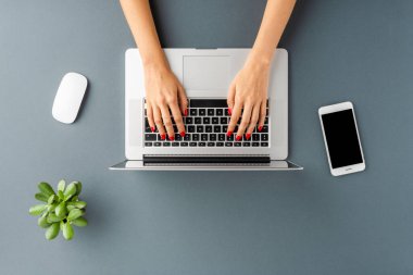 Gri ofis bilgisayarında dizüstü bilgisayar kullanan kadın ellerinin yukarıdan çekimleri. İş geçmişi. Düz yatıyordu