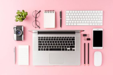 Pembe arka planda dizüstü bilgisayar ve iş aksesuarlarıyla modern çalışma alanı konseptinin genel çekimi. Ofis masaüstü. Düz yatıyordu