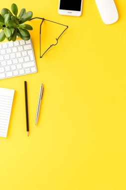 Sarı arka planda iş aksesuarları ve kopyalama alanı olan zarif bir çalışma alanı. Ofis masaüstü