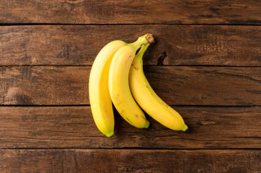 Ahşap arka planda bir sürü taze muz. Üst görünüm