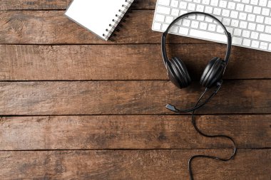 Kulaklık ve bilgisayar, kopyalanmış ahşap masada. Çağrı merkezi kavramı