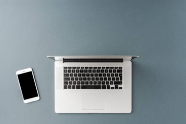 Gri arka planda dizüstü bilgisayar ve cep telefonu görüntüsü. Ofis masaüstü
