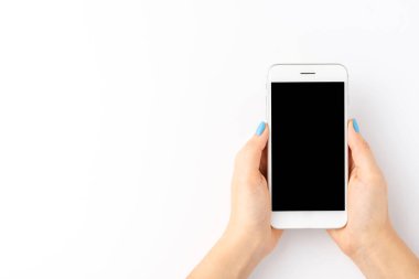 Beyaz arka planda boş ekranlı akıllı telefon kullanan kadın ellerinin yukarıdan çekilmiş görüntüleri. Üst görünüm