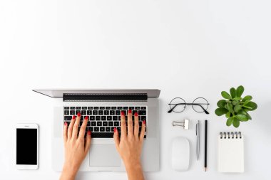 Dizüstü bilgisayarda çalışan kadın elleri. Telif alanı beyaz arka planda aksesuarları olan modern ofis masaüstü. Üst görünüm