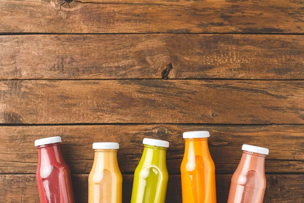 Taze meyve ve sebze suyu şişelerde eski ahşap arka planda kopyalanmış