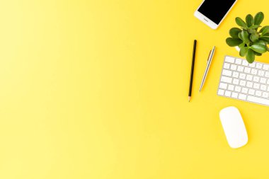 Sarı arka planda iş aksesuarları olan modern bir iş yeri. Ofis masaüstü