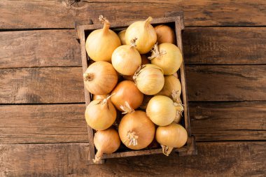 Kırsal ahşap arka planda kutuda taze beyaz soğan resmi.