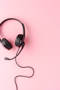 Pembe arka planda yardım masası kulaklığı. Çağrı merkezi konsepti. Üst görünüm
