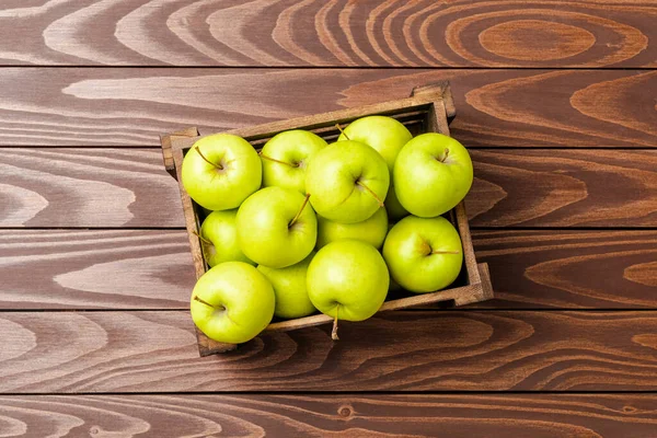 Ahşap masada yeşil elma resmi.