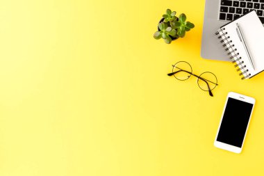 Sarı arka planda iş aksesuarları ve kopyalama alanı olan zarif bir çalışma alanı. Ofis masaüstü