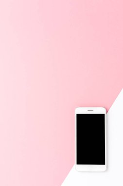 Telif uzayı olan soyut pembe ve beyaz arkaplan üzerinde boş ekranlı akıllı telefonun yukarıdan çekilmiş görüntüsü. Düz yatıyordu