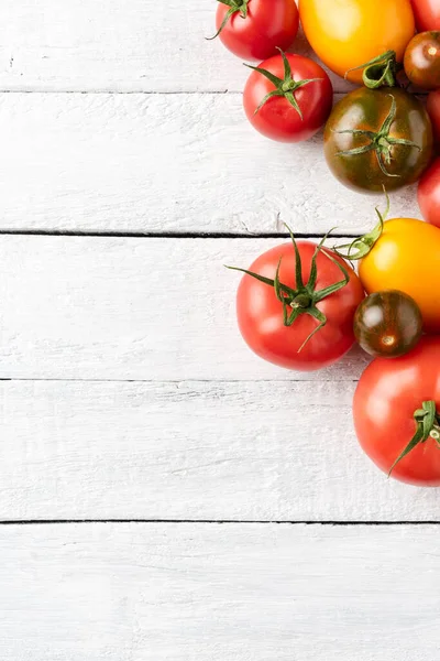 Telif alanı olan beyaz masada kırmızı, sarı ve yeşil domatesler. Yemek arkaplanı. Üst görünüm