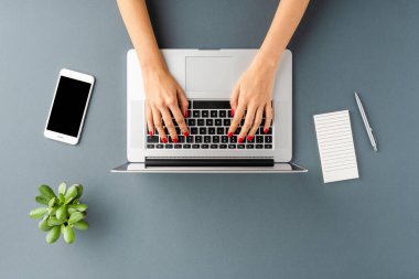 Kadın elleri gri masada aksesuarlarla birlikte dizüstü bilgisayarda çalışıyor. İş geçmişi. Düz yatıyordu