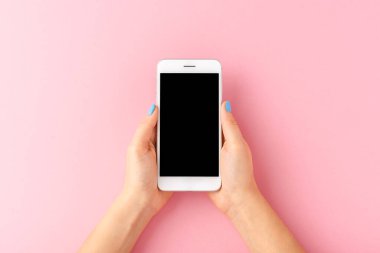 Mavi tırnaklı bir kadın, pembe arka planda boş ekranlı akıllı telefon kullanıyor. Üst görünüm