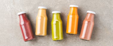 Taze meyve ve sebze suları beton arka planda şişelerde. Pankart