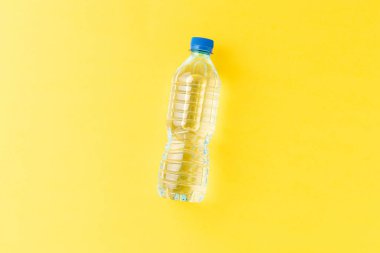 Sarı arka planda, küçük plastik şişedeki maden suyunun tepe noktası.