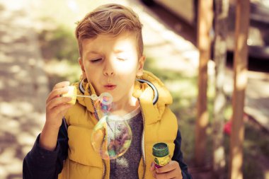Small kid having fun while using bubble wand outdoors. 
