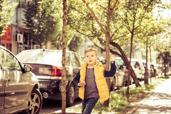 Small Kid Playing Outdoors While Catching Soap Bubbles Street — ストック写真
