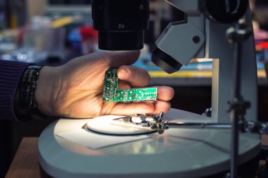 Close up of engineer examining computer component under the microscope. 