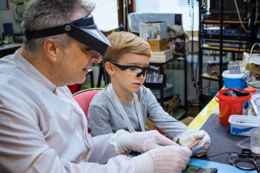 Science teacher teaching his student how to repair computer part in IT laboratory during engineering lesson.