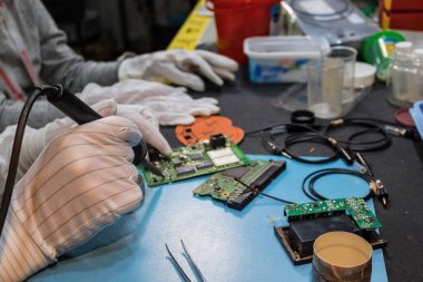 Close up of IT technician soldering elements on microchip of a mother board. 