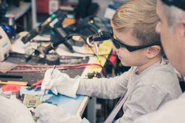 Elementary student learning how to repair cpu board with help of his teacher in tech laboratory. 