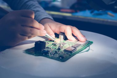 Close up of kid using brush and cleaning circuit board in IT laboratory.