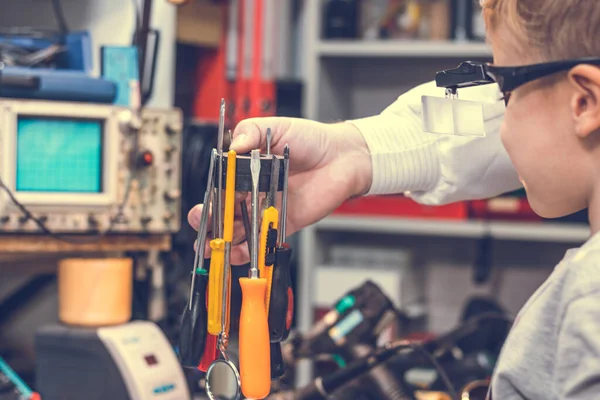 Close up of small student and physics teacher performing experiment with magnet and work tools in engineering laboratory.